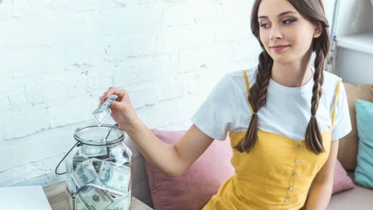 Young woman putting money in a jar