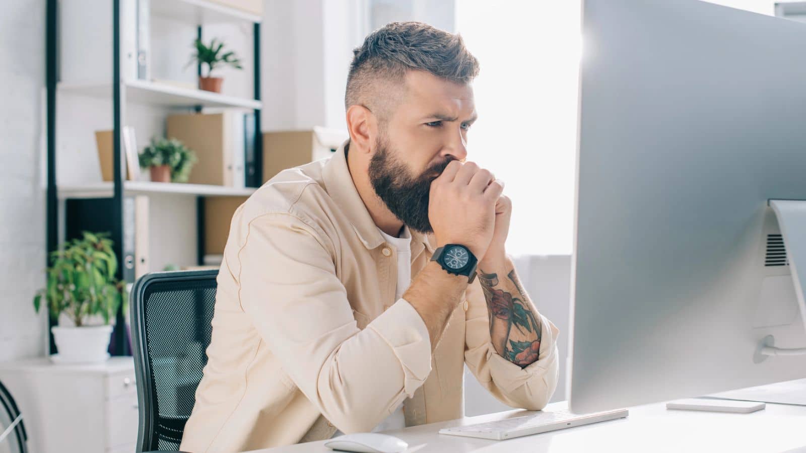 Man looking at his compute holding his hands to his face