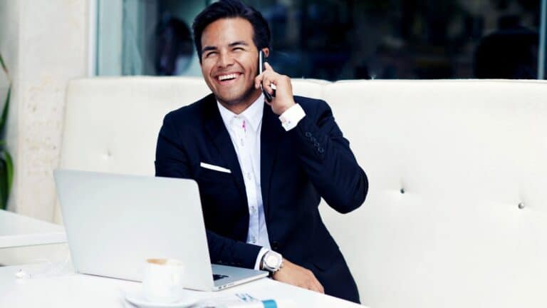 Wealthy businessman using his laptop and talking on cell phone