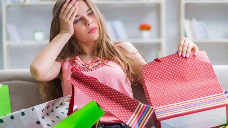 Woman covered in shopping bags looking regretful