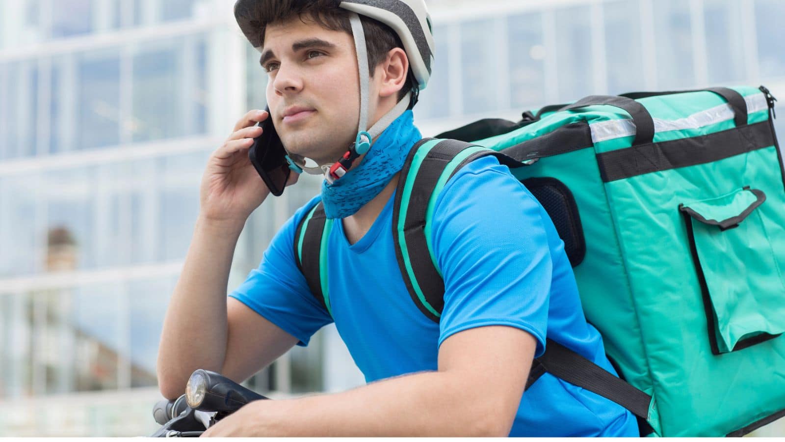 Man on bike talking on the phone and carrying a delivery bag on his back
