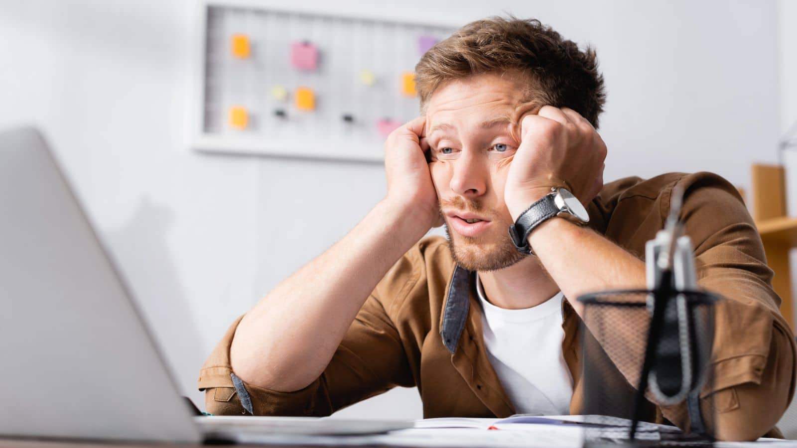Man looking exhausted at his laptop
