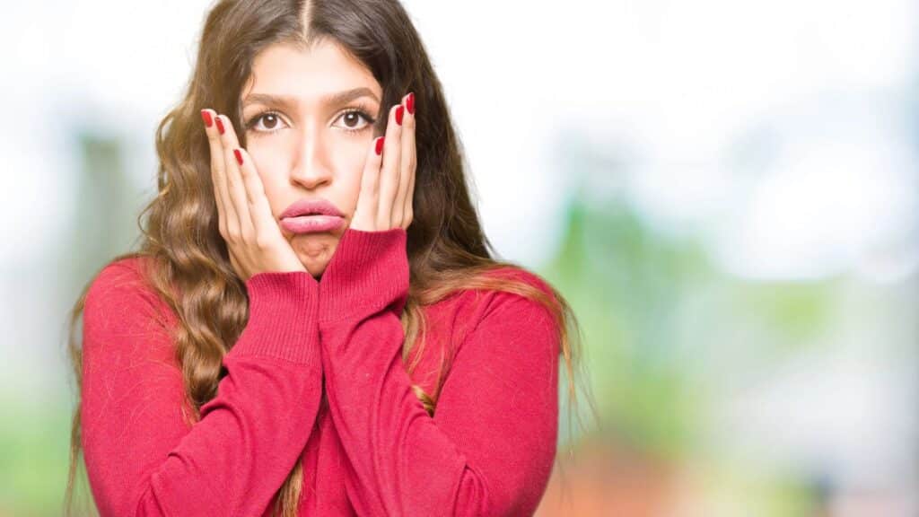 Young woman looking frustrated and holding her face with her hands