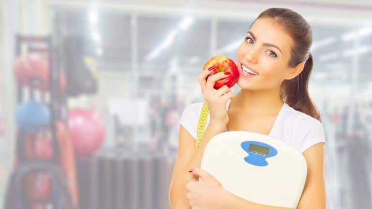 Young woman holding a scale and an apple