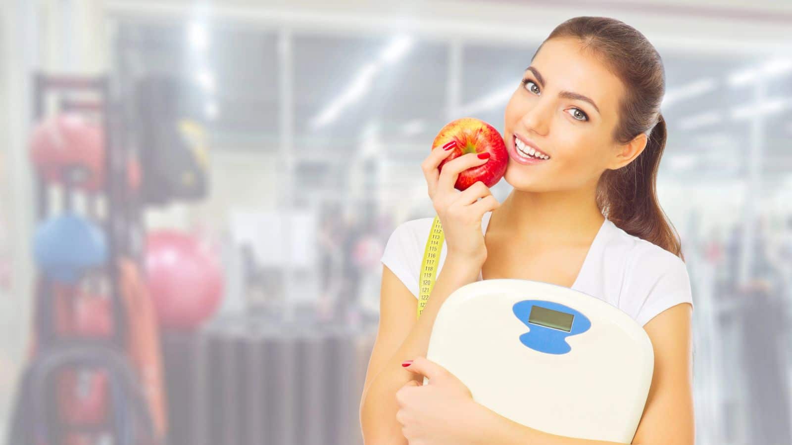 Young woman holding a scale and an apple