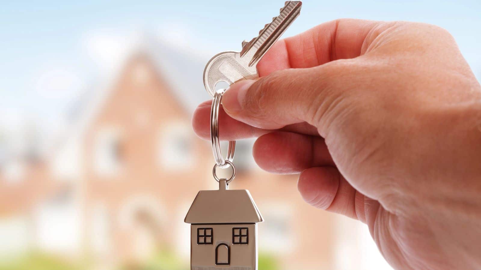 Hand holding a key with a house keychain
