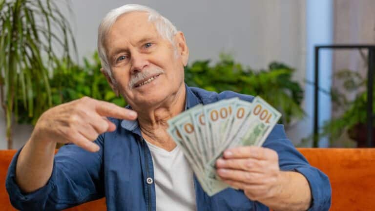 Old man holding a bunch of hundred dollar bills