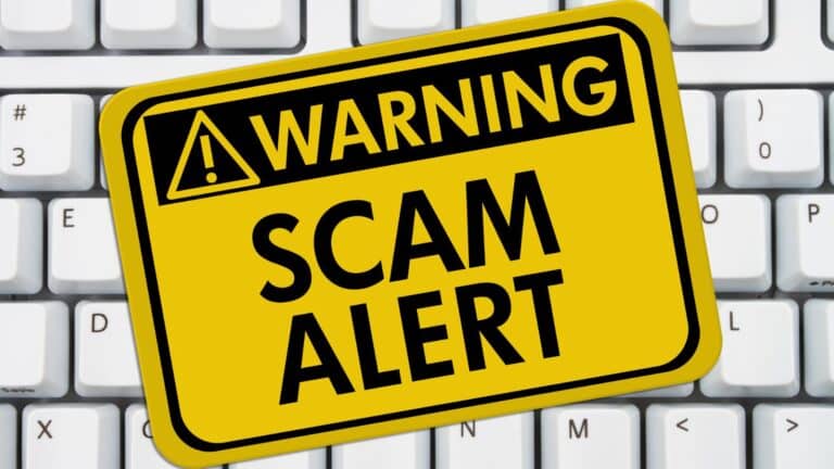 Computer keyboard with yellow sticker that reads: warning scam alert"