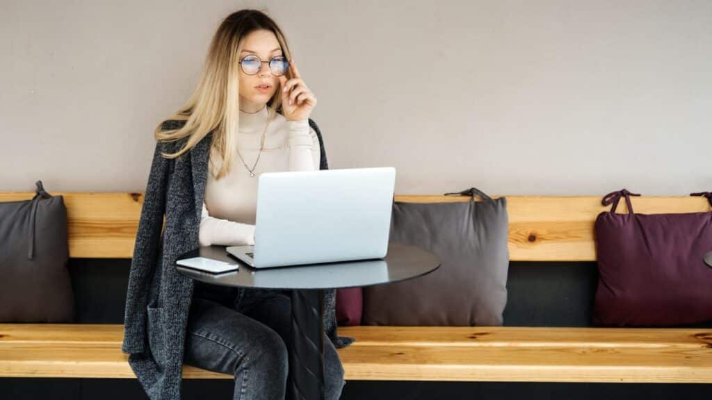Blonde woman sitting on a bench working on her laptop
