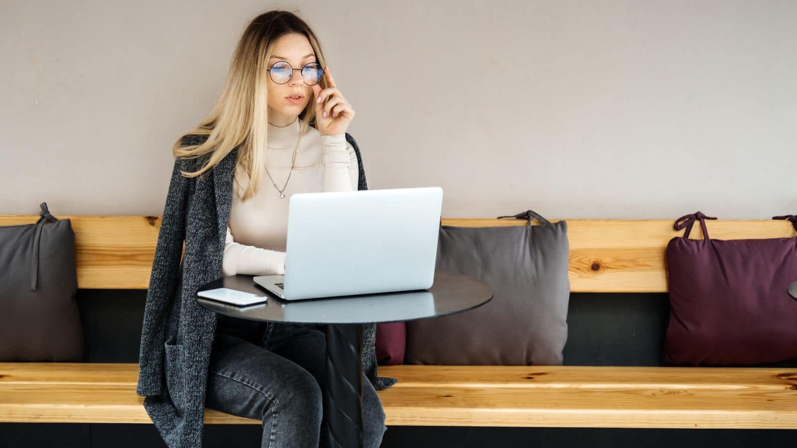 Blonde woman sitting on a bench working on her laptop