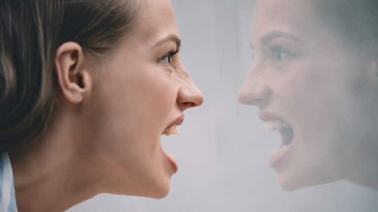 Angry young woman yelling at her reflection