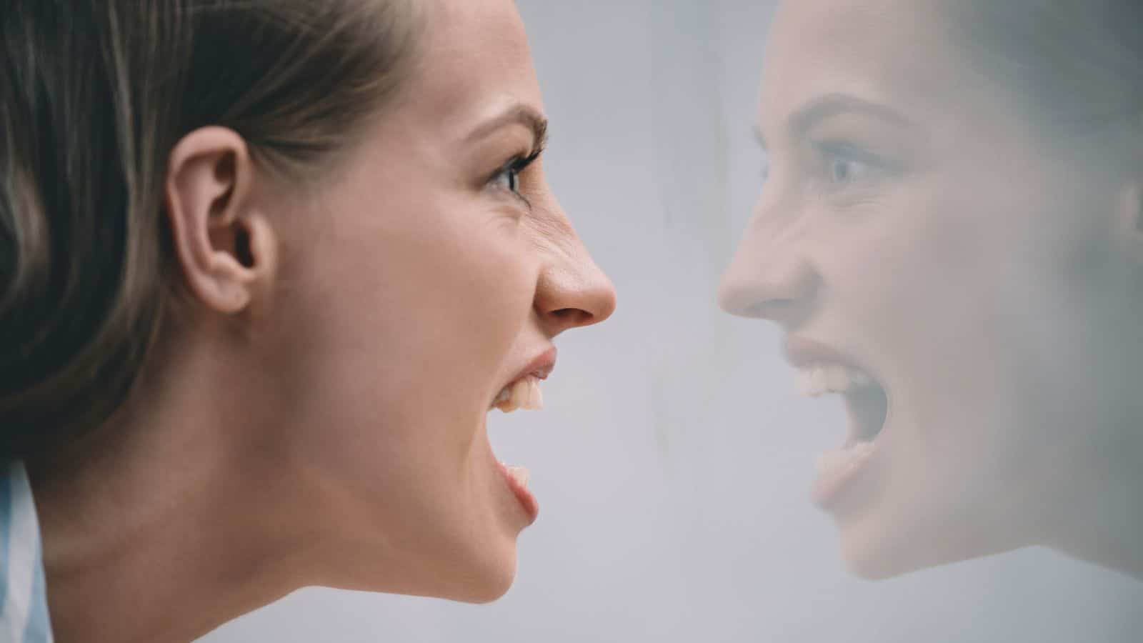 Angry young woman yelling at her reflection