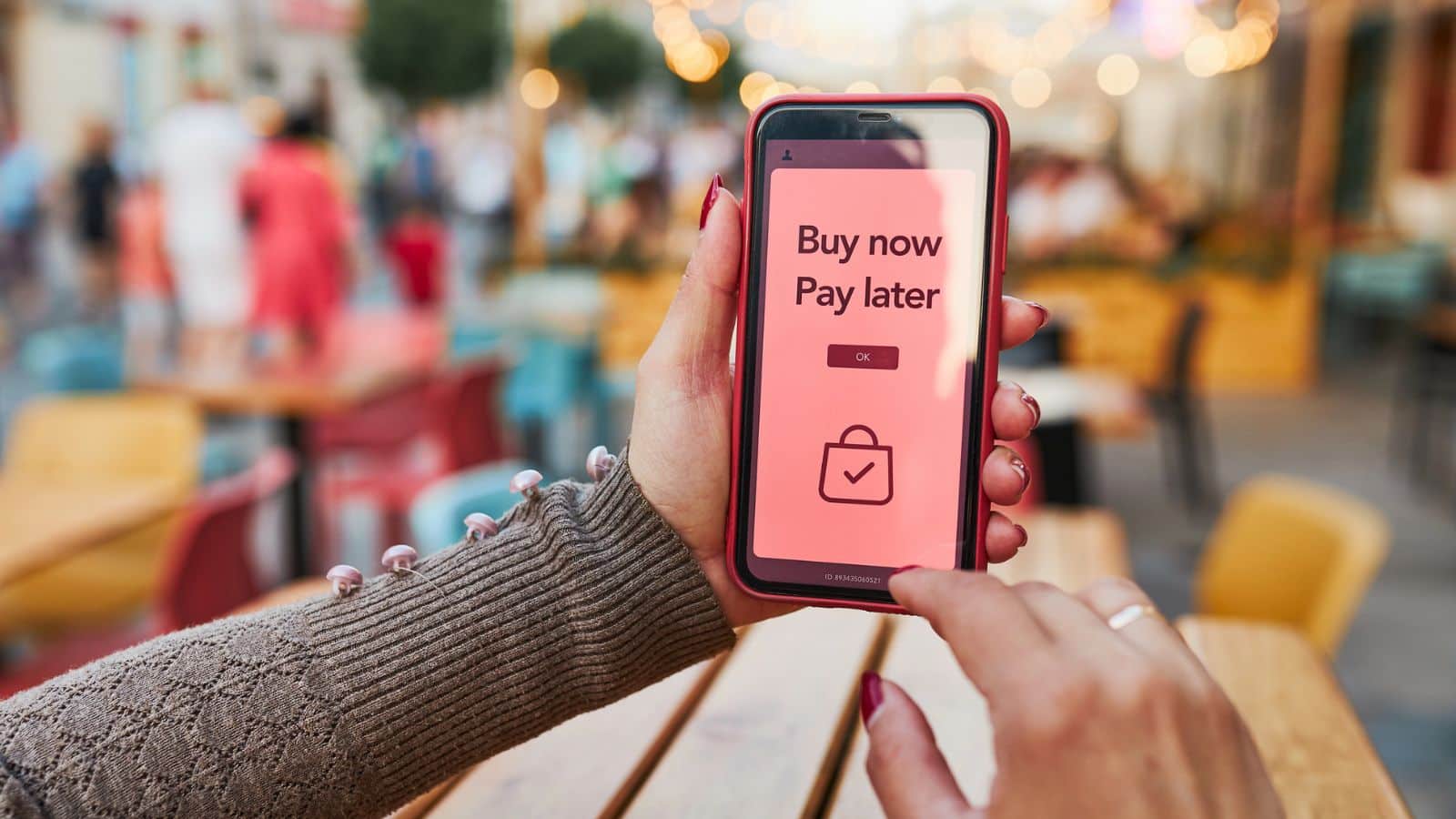 Person in a store holding a phone using buy now pay later