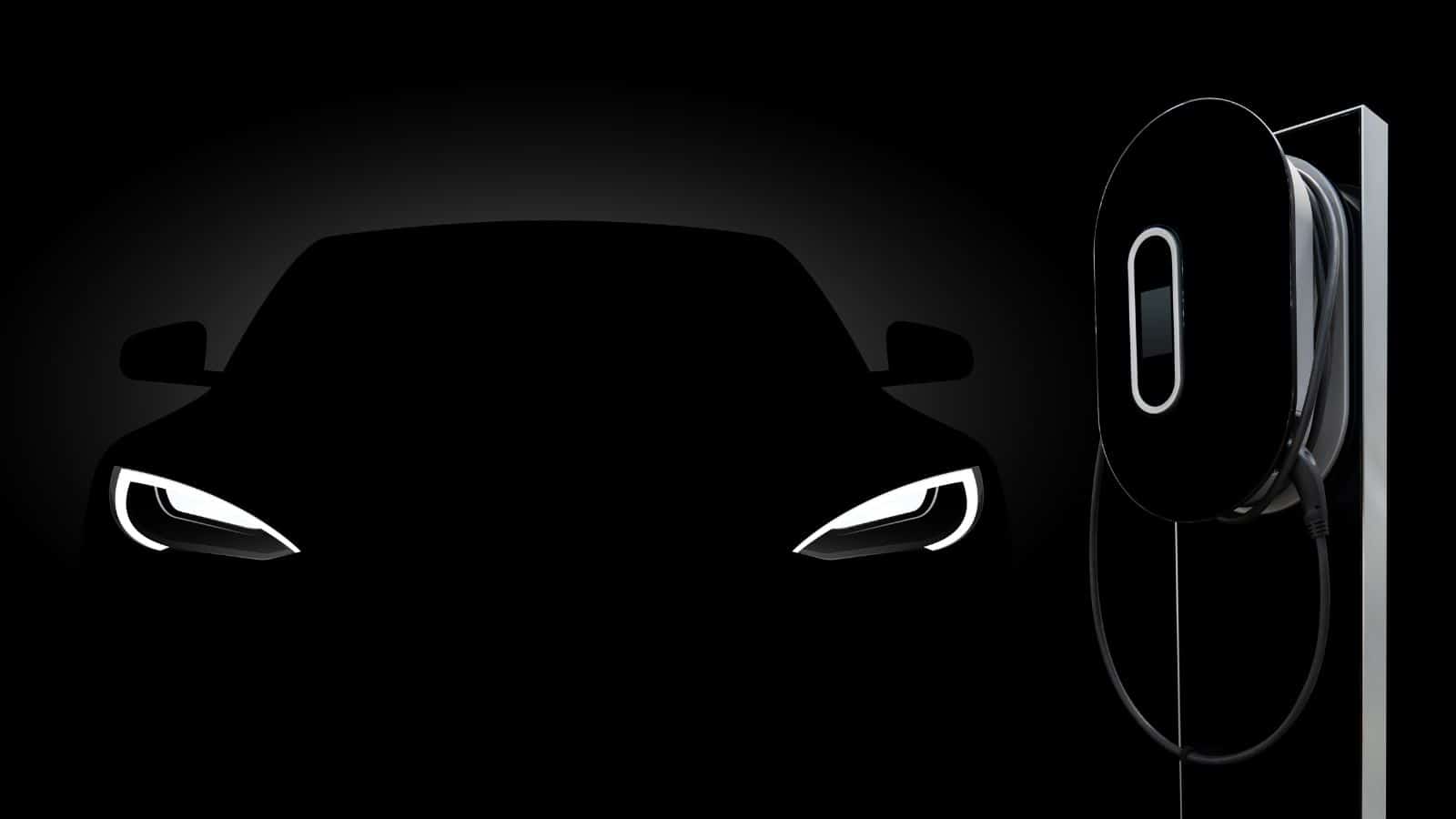 Dark room with a dark electric vehicle with lights on and charging station