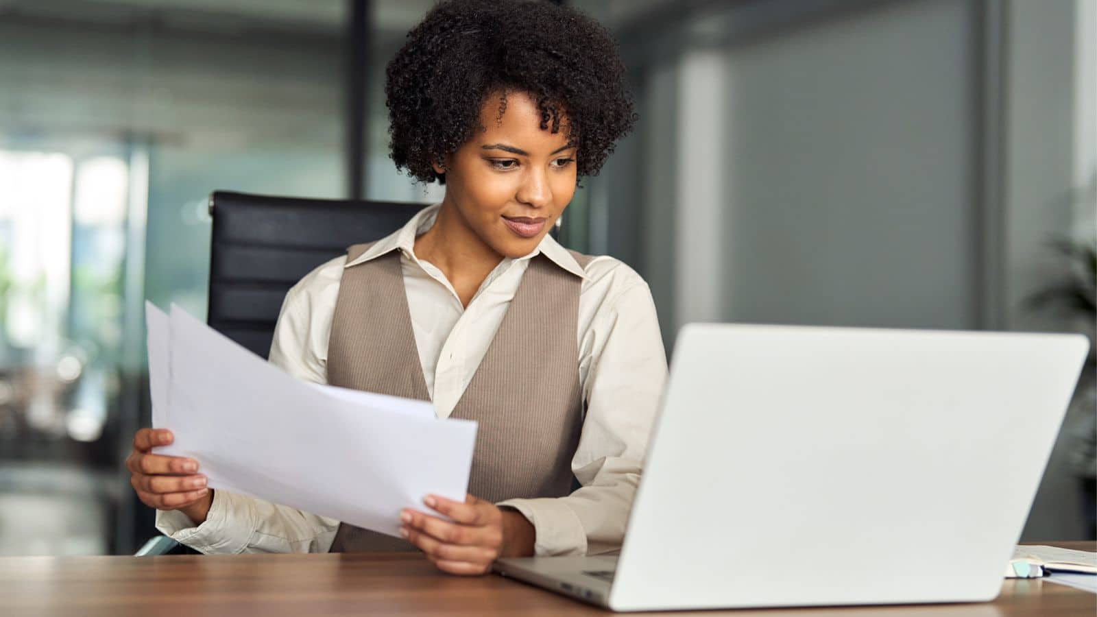 Woman looking at papers and working on her laptop