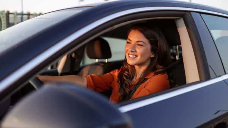 Young woman sitting in her car smiling
