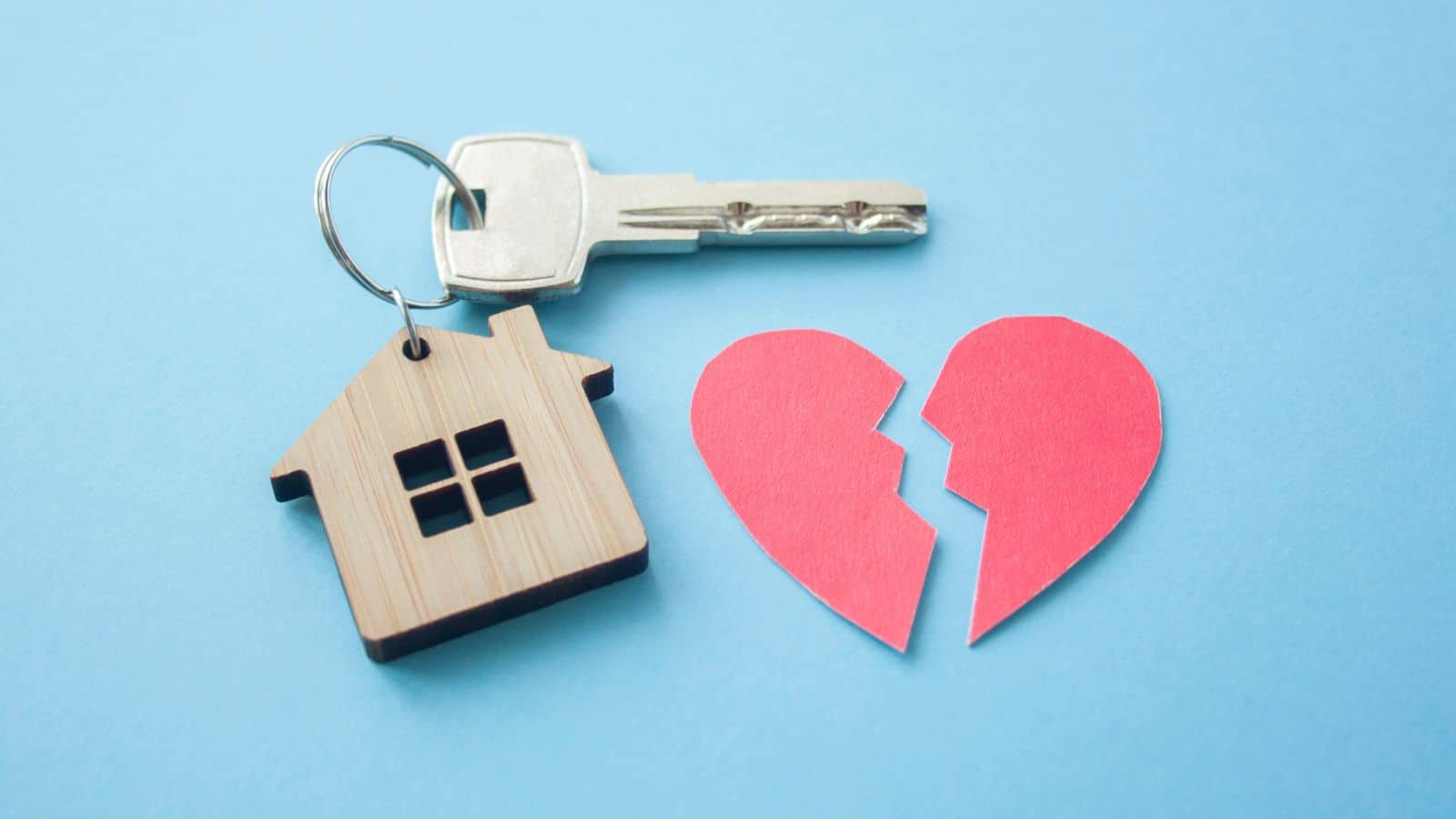 Paper heart broken, housekey and keychain on blue background