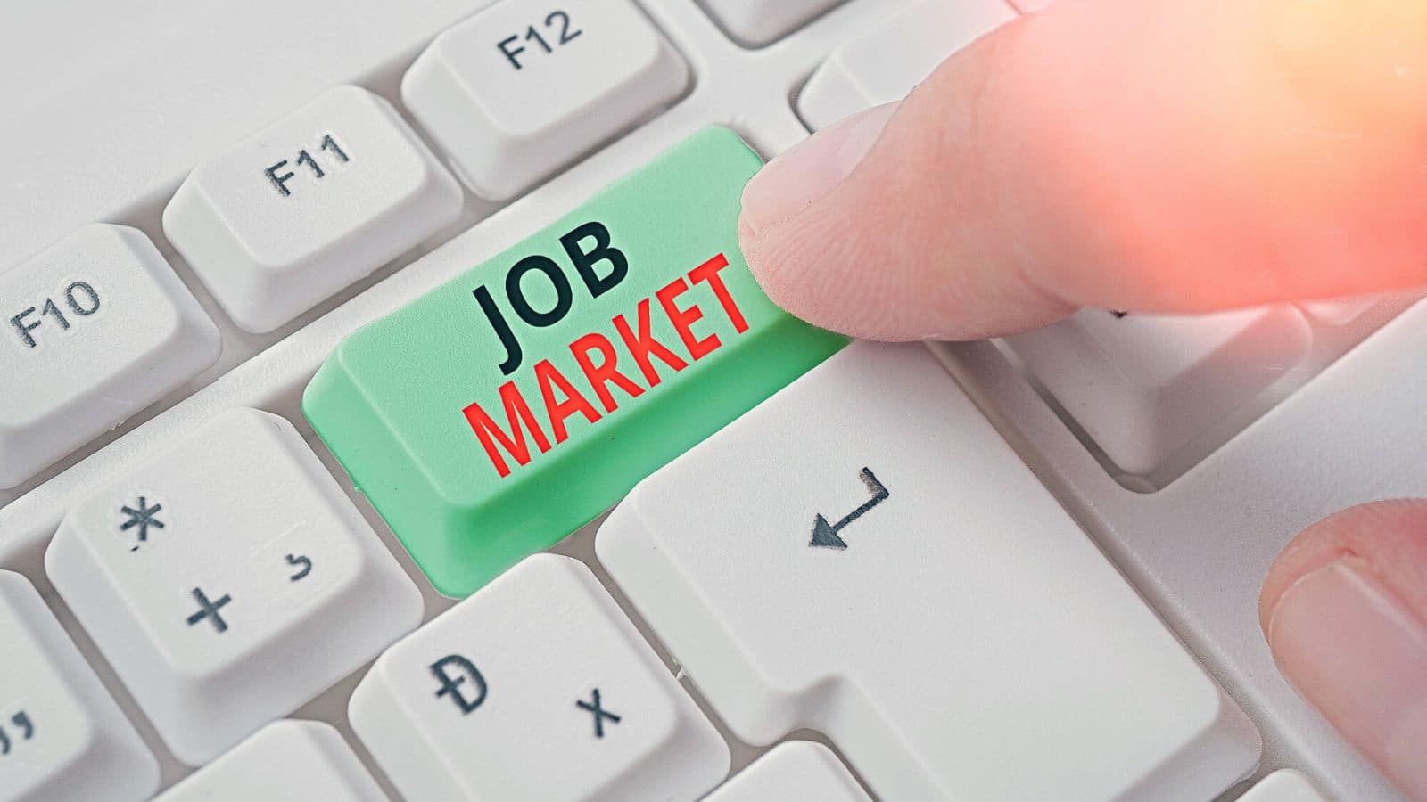 Finger pressing a key on a keyboard that is labeled "job market"