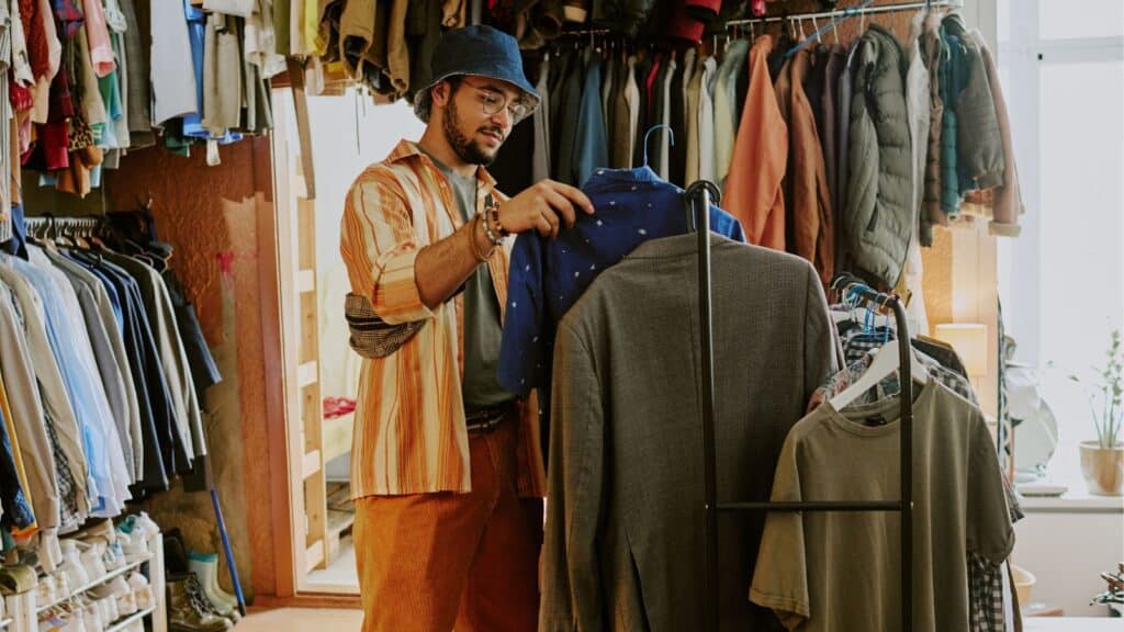 Man browsing through clothing in a thrift store