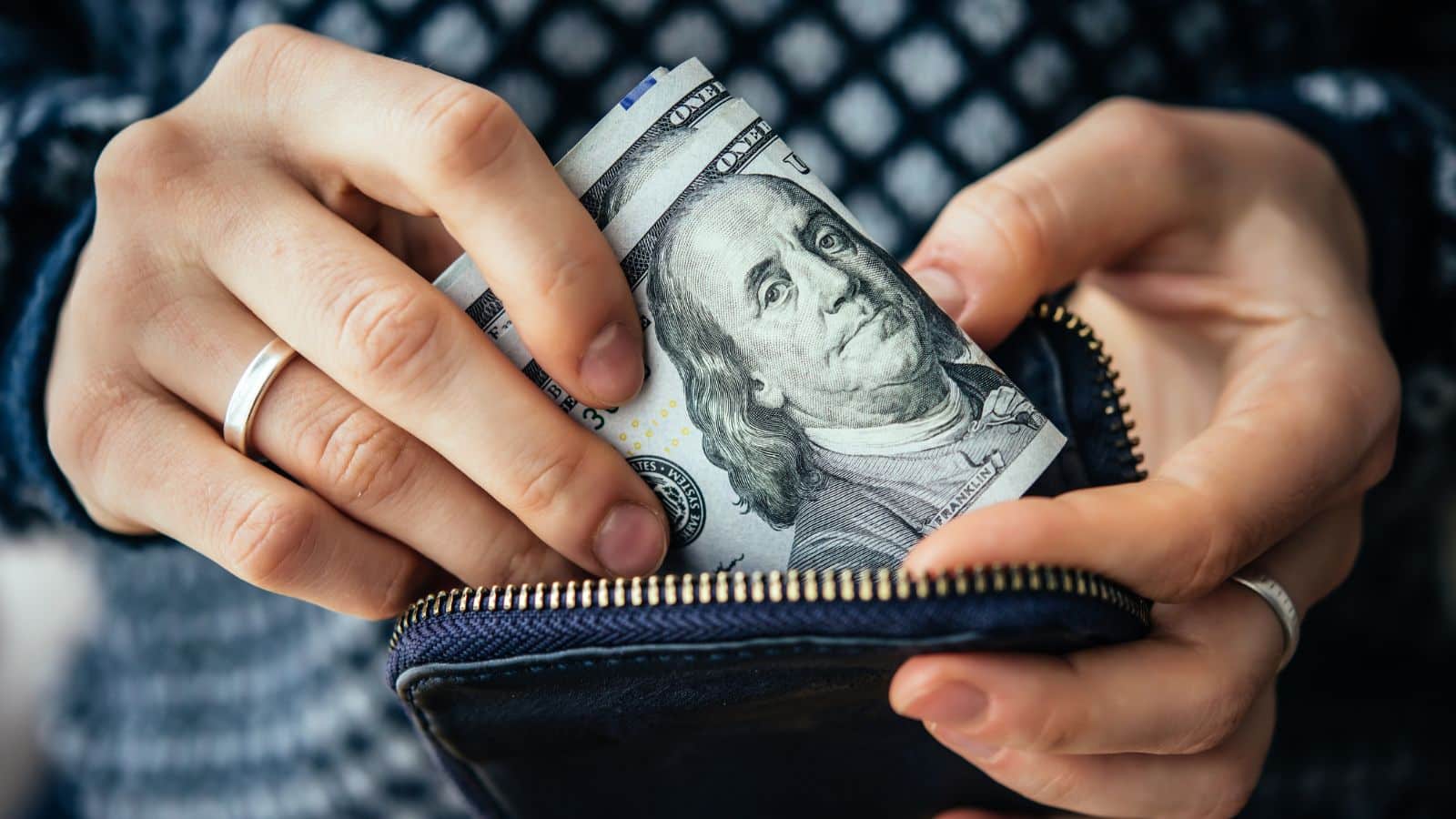 Man putting a wad of cash into his wallet