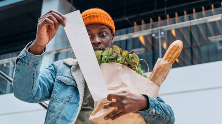 Man shocked by his grocery total and looking at his receipt