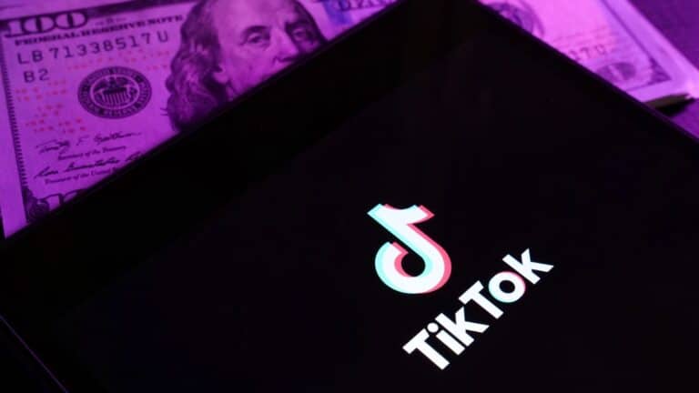 TikTok logo on a device with money behind it