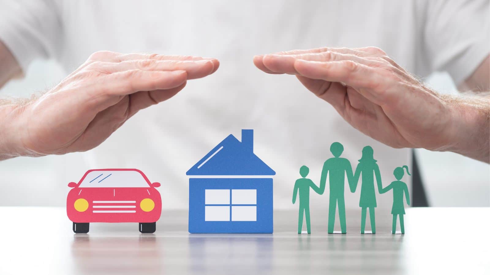 Person holding their hands above a small car, house, and family