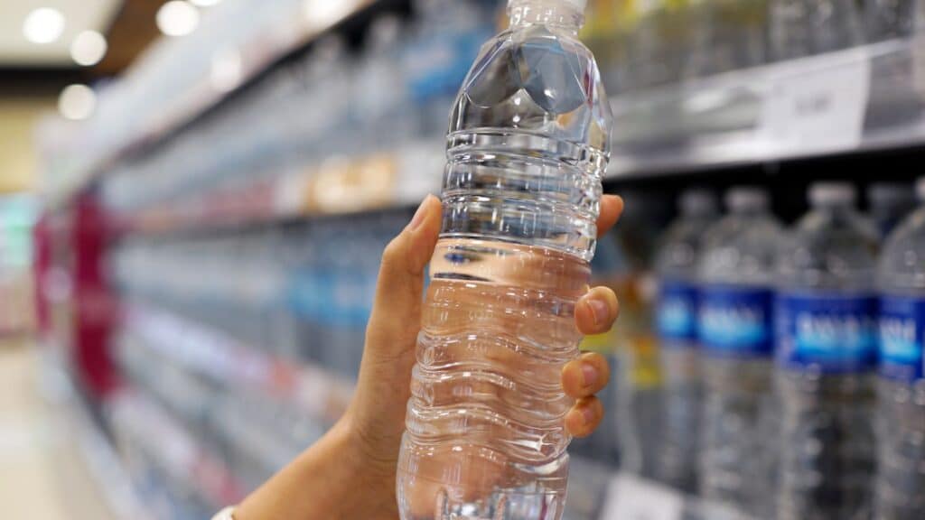 Person holding a water bottle in a store