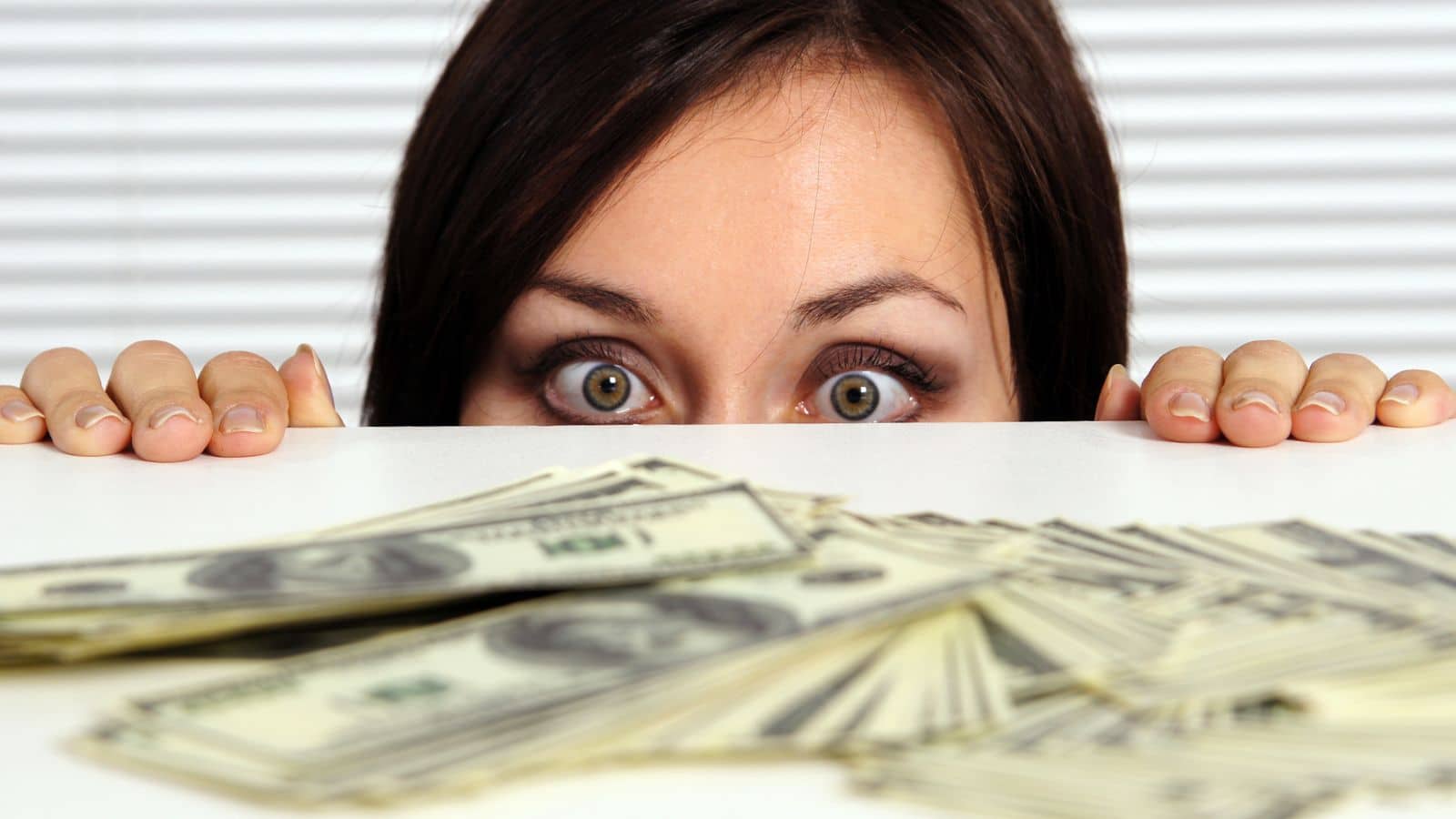 Woman crouched down and looking closely at a table filled with money