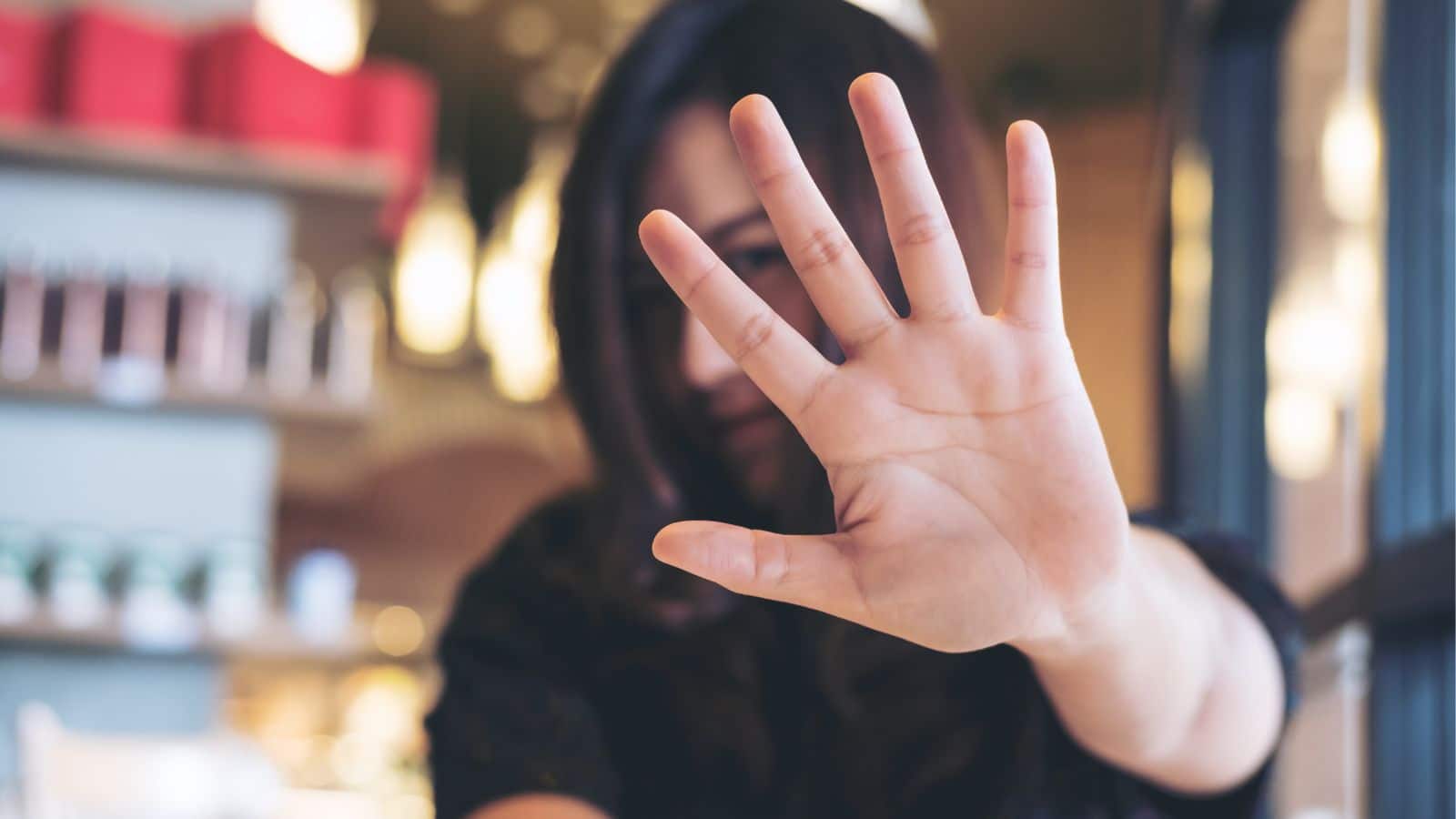 Young woman holding her hand out as if to say "no"