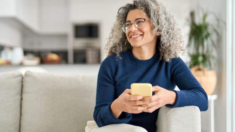 Mature woman sitting on the couch holding her phone