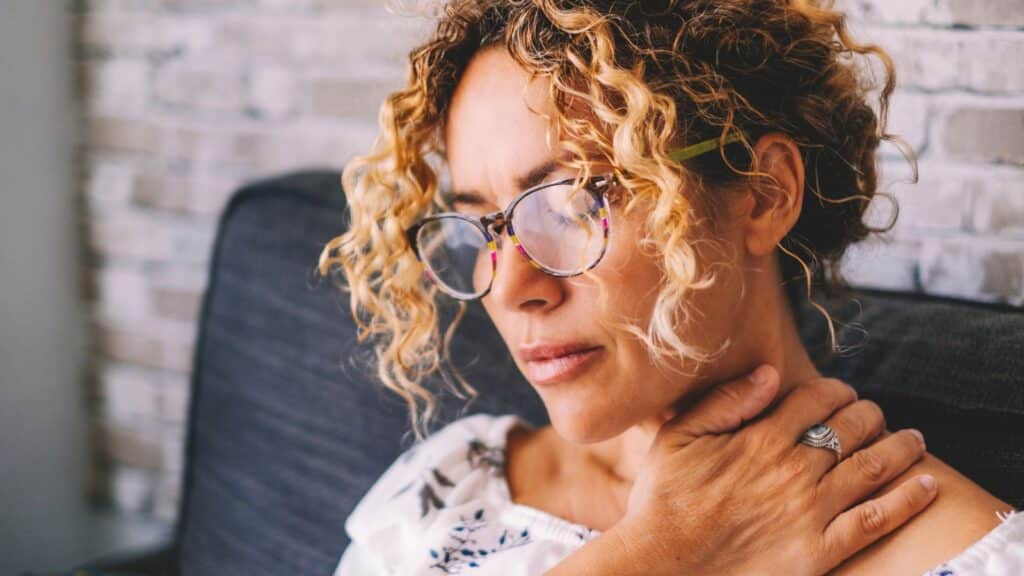 Woman with her hand on her shoulder and looking stressed