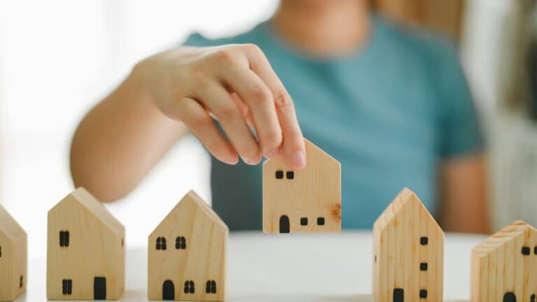 Woman putting little wooden houses in a row