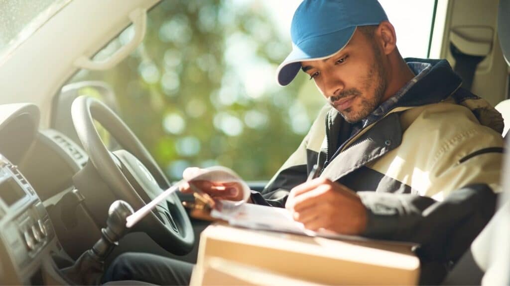 Delivery driver sitting in his truck looking through paperwork
