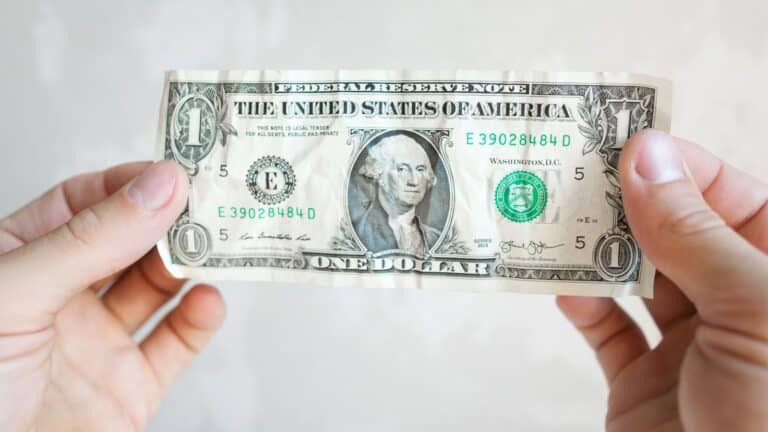 Hands holding a wrinkled one dollar bill
