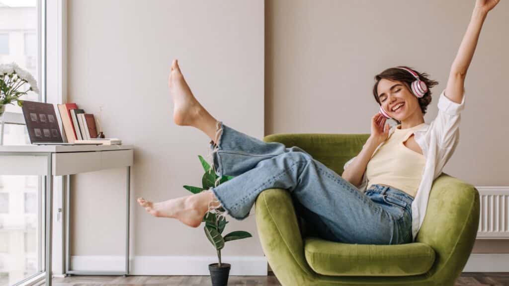 Young brunette wearing headphones lounging in a green chair