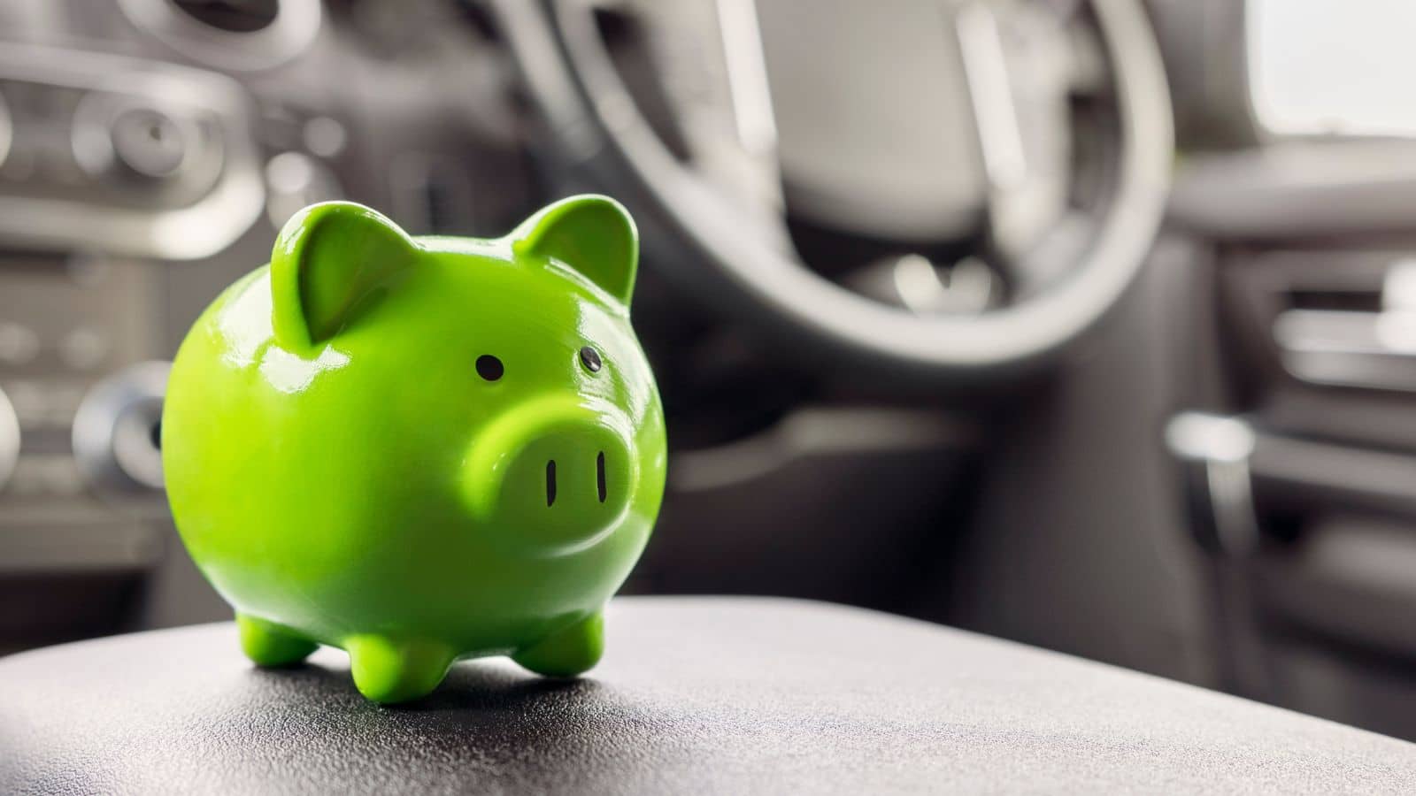 Green piggy bank sitting on a car console