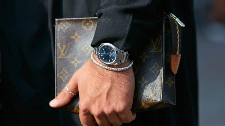 Man holding a Louis Vuitton bag wearing a Rolex watch