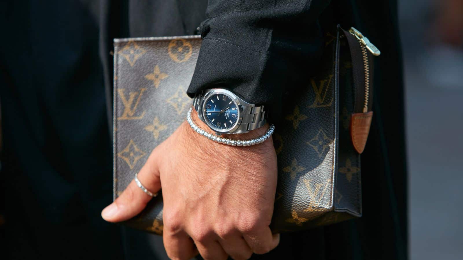 Man holding a Louis Vuitton bag wearing a Rolex watch