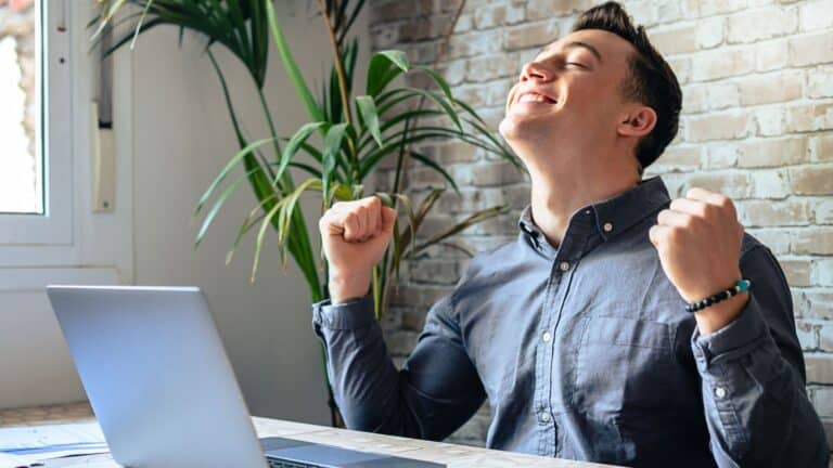 Male employee sitting ask his desk looking excited