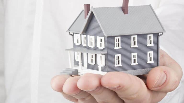 Person holding a tiny model home in their hand