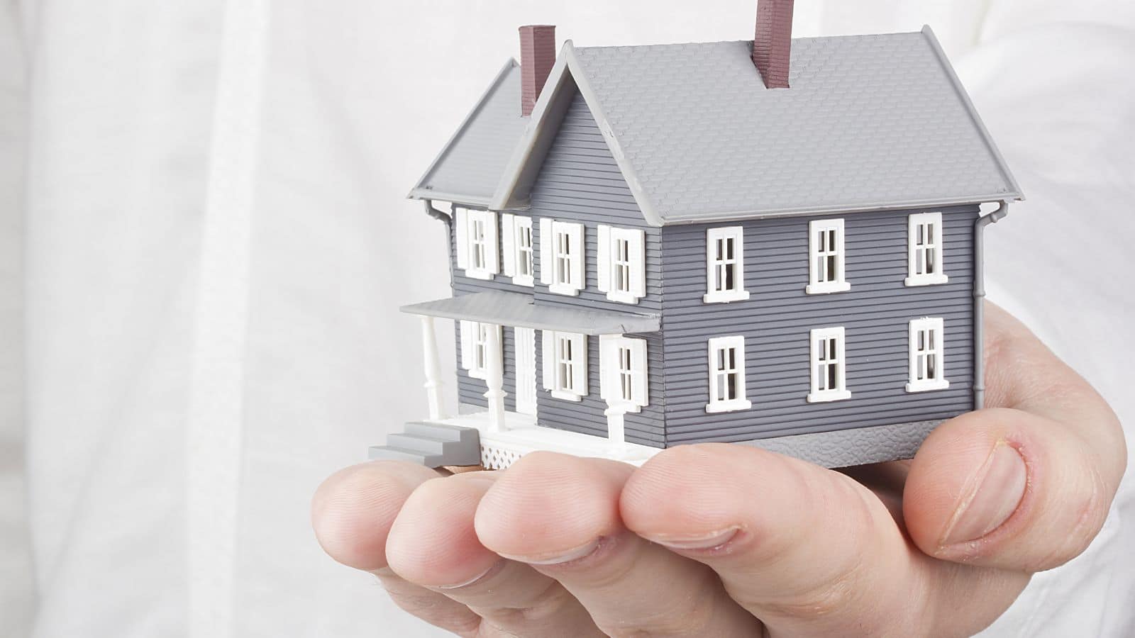 Person holding a tiny model home in their hand