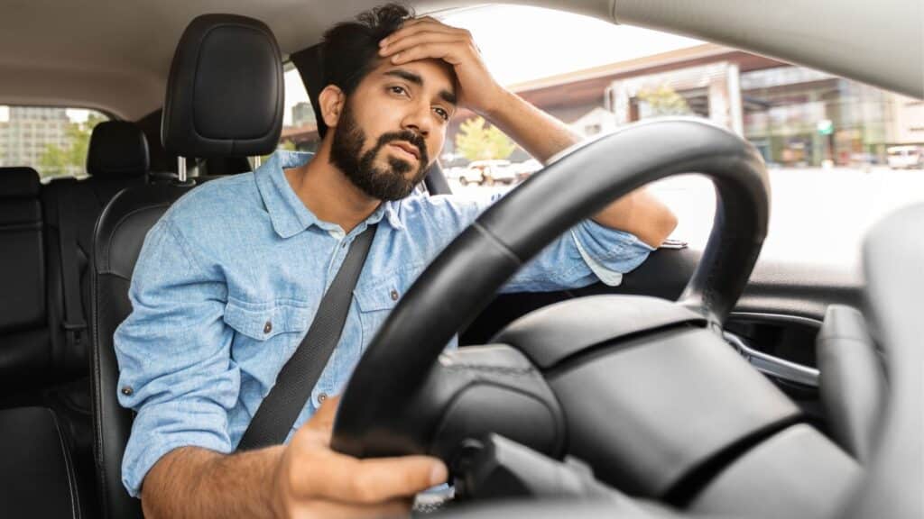 Man sitting in his car looking very upset