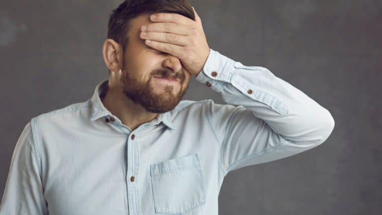 Man covering his eyes and making a face where he looks like he's regretting something