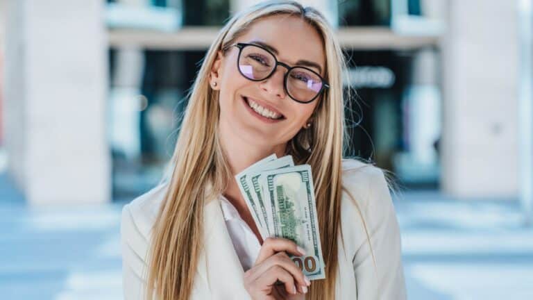 Young blonde woman holding a handful of money