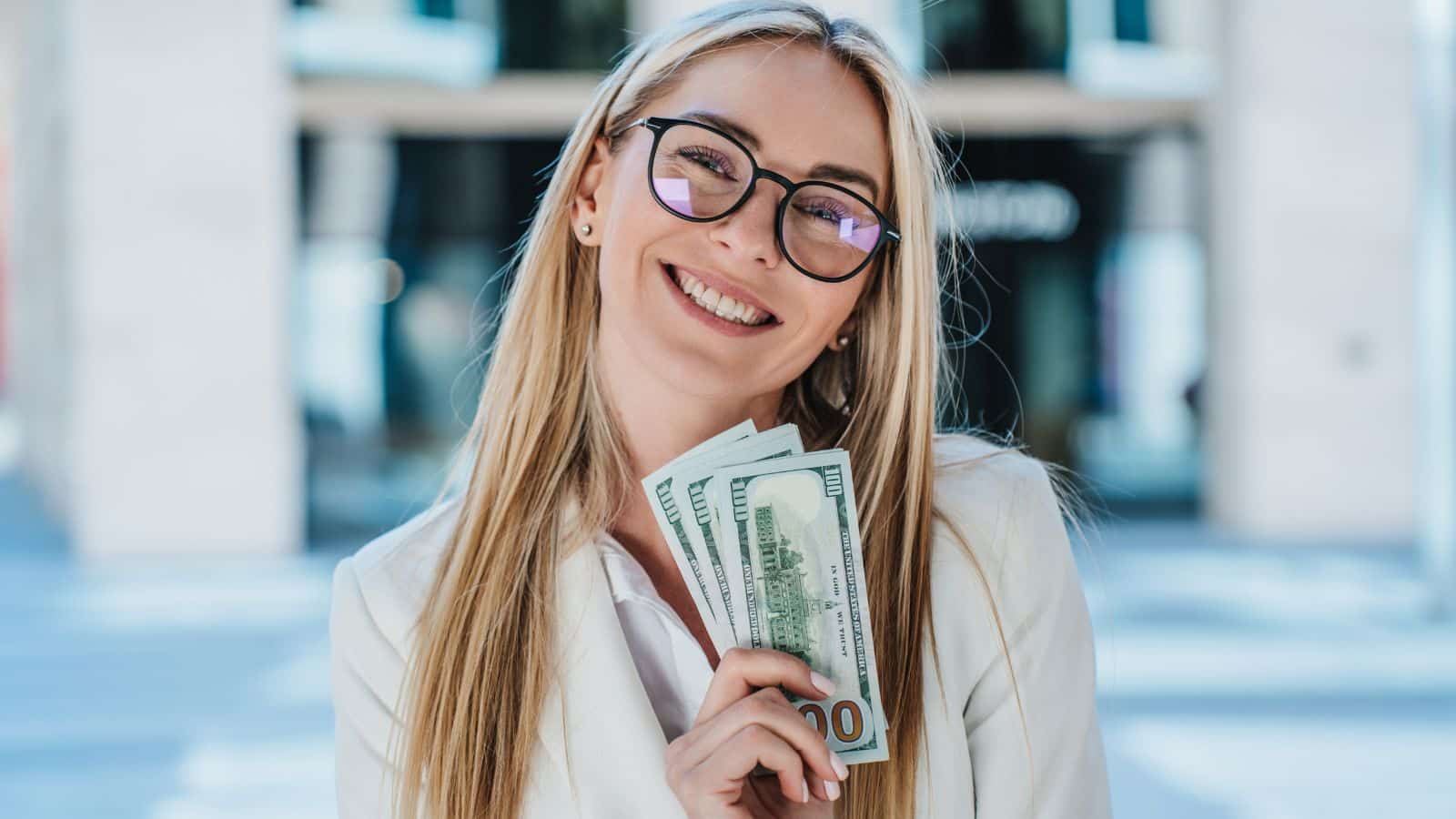 Young blonde woman holding a handful of money