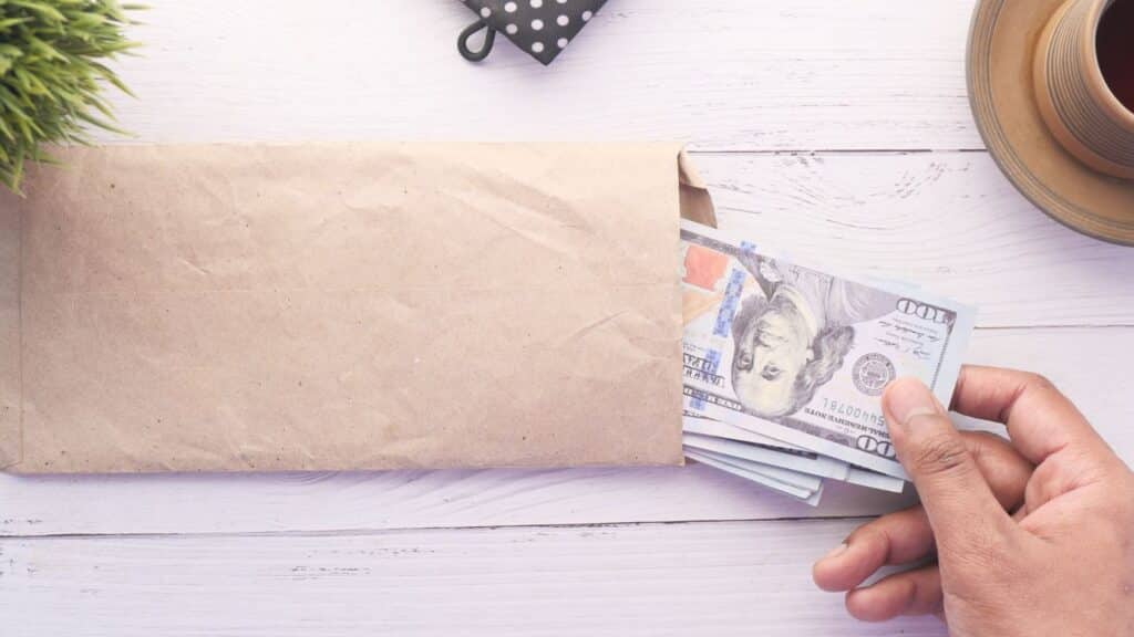 Man's hand putting cash into an envelope