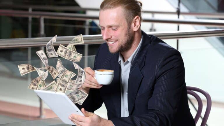 Businessman making money from his tablet while drinking coffee