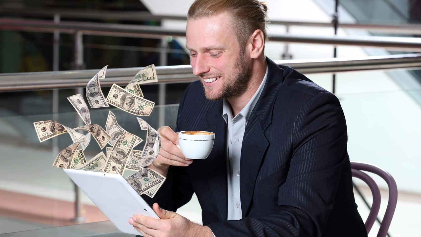 Businessman making money from his tablet while drinking coffee