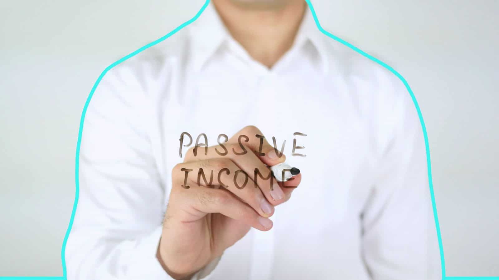 Man writing the words "passive income" on glass